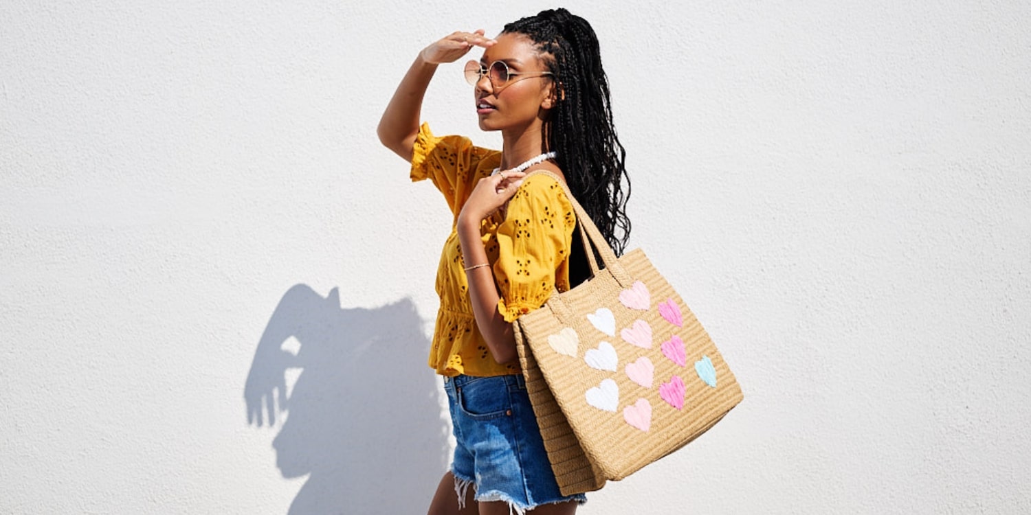 Model wearing a beach resort outfit with a tote