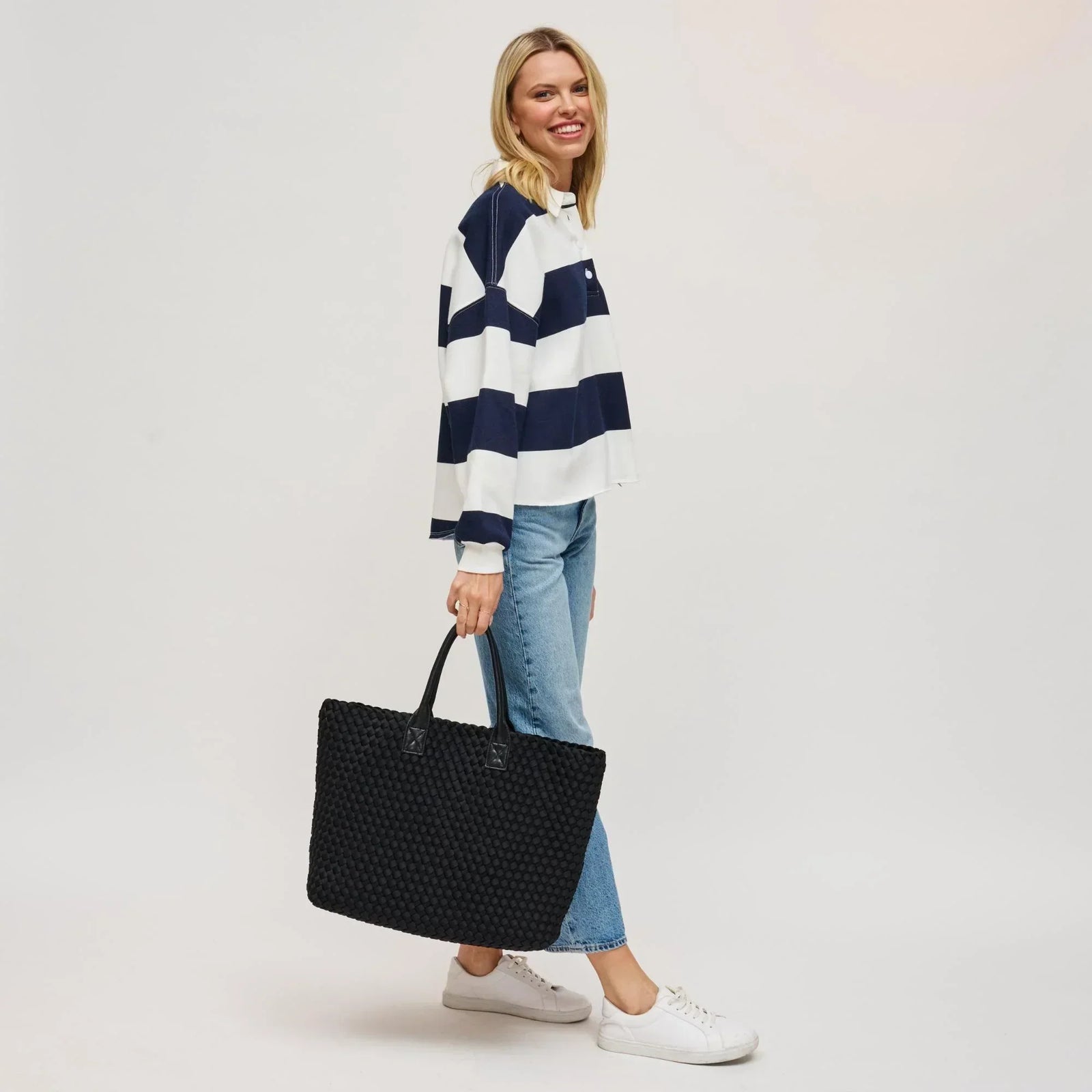 model wearing a striped shirt and jeans with a black tote bag