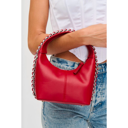Woman holds bright red purse with chain